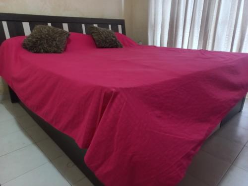 a bed with a pink blanket on top of it at Amaya Inn in Rajagiriya