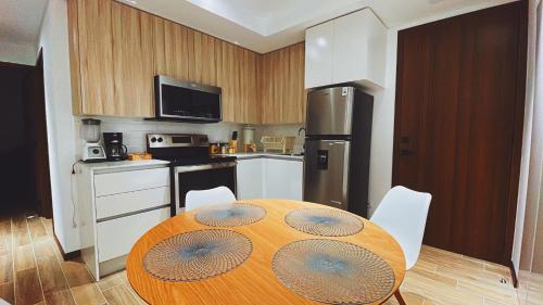 uma cozinha com uma mesa de madeira e uma cozinha com um frigorífico em Apartamento Deluxe Near Aeropuerto zona 13 em Guatemala
