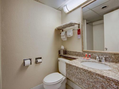 a bathroom with a toilet and a sink and a mirror at Scottish Inn Whippany in Whippany
