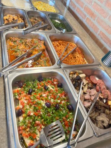 a buffet filled with different types of food in trays at Hostel do Cabral in Piracicaba