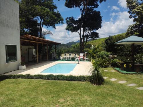 a person standing by a swimming pool in a yard at Casa da montanha, sítio em Secretário (Petrópolis) in Petrópolis