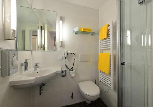 a white bathroom with a sink and a toilet at Hotel Ratskeller in Salzgitter