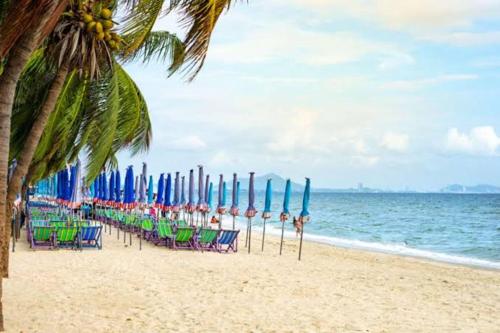 uma fila de cadeiras de praia e guarda-sóis numa praia em The Beach Bangsaen Condo 327/30 em Ban Bang Saen (1)