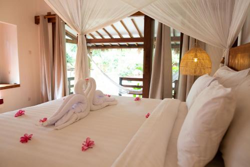 two swans sitting on top of a bed with flowers at Island View Bar & Bungalow in Gili Air