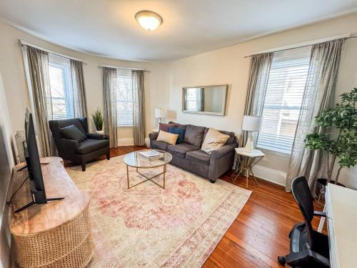 a living room with a couch and a tv at Sunny,spacious, Sleeps 4, Steps To Mbta,hospitals in Brookline