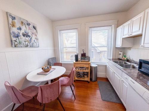 a kitchen with a white table and chairs in a kitchen at Sunny,spacious, Sleeps 4, Steps To Mbta,hospitals in Brookline