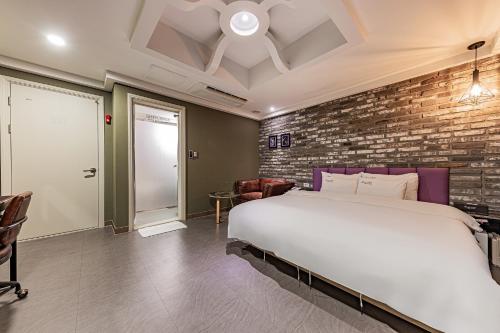 a bedroom with a large bed and a brick wall at Hotel Soseol Smith in Cheonan