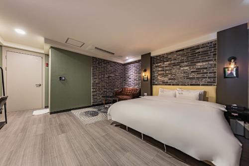a bedroom with a large bed and a brick wall at Hotel Soseol Smith in Cheonan
