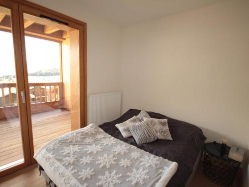 Cette chambre comprend un lit avec des oreillers et un balcon. dans l'établissement Les Saisies - Appartement 6 pers, WiFi, Parking, équipements neufs - FR-1-293-398, à Hauteluce