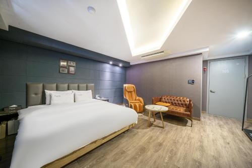 a bedroom with a large bed and a chair at Hotel Soseol Smith in Cheonan