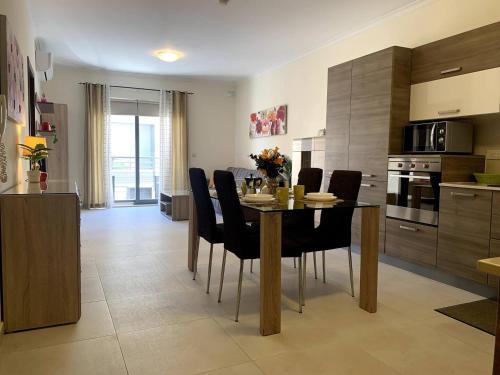 a kitchen and dining room with a table and chairs at Cara Flats By Homely in Mellieħa
