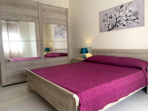 a bedroom with a large bed and a mirror at Cara Flats By Homely in Mellieħa