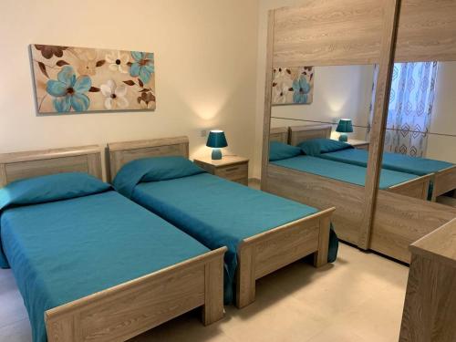 a bedroom with two beds and a mirror at Cara Flats By Homely in Mellieħa