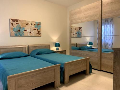 a bedroom with two beds and a large mirror at Cara Flats By Homely in Mellieħa