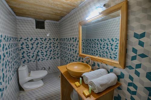 uma casa de banho com um lavatório, um WC e um espelho. em Jaisalmer Unique Desert Camp em Sām