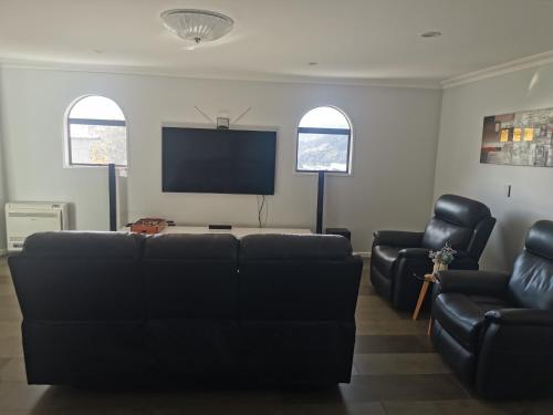 a living room with a couch and a flat screen tv at Luxury Harbour view in Dunedin