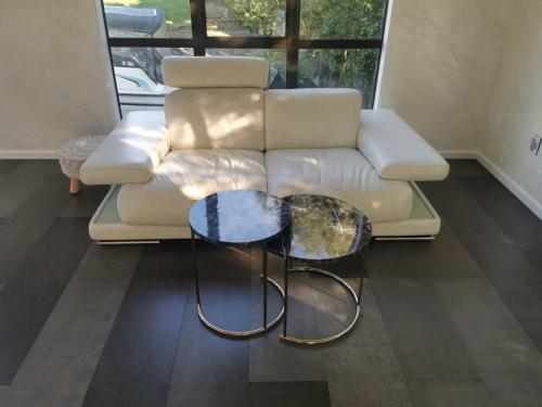 a living room with a white couch and two tables at Luxury Harbour view in Dunedin