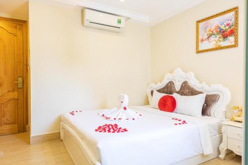 a bedroom with a white bed with red flowers on it at Happy Star Hotel Nha Trang in Nha Trang