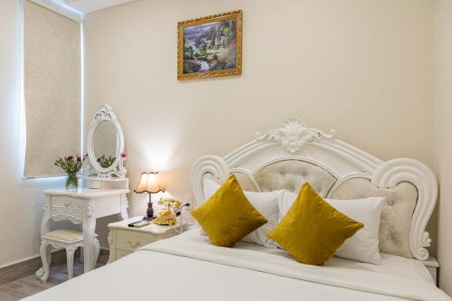 um quarto com uma grande cama branca com almofadas amarelas em Happy Star Hotel Nha Trang em Nha Trang