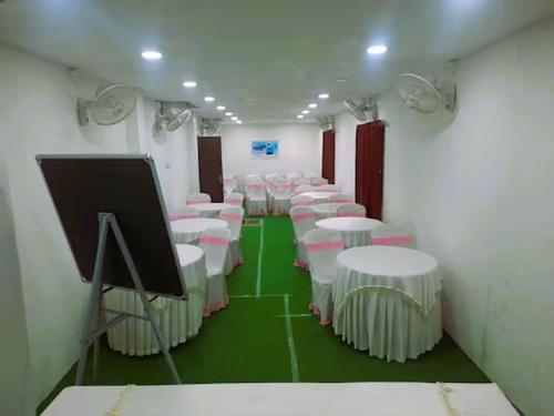a room with rows of tables and white chairs at Hotel Archana in Madurai
