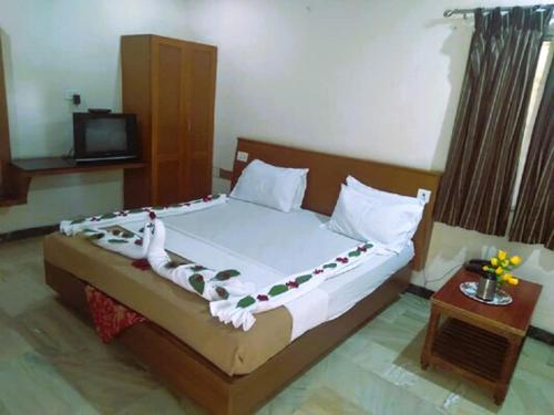 a bedroom with a bed and a tv and a bed sidx sidx sidx at Hotel Archana in Madurai