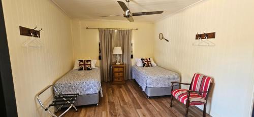 een slaapkamer met 2 bedden en een plafondventilator bij The Wattle Lodge in Glendon Brook