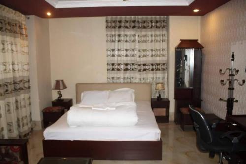 a bedroom with a bed and a desk and a chair at 78 Firoza Inn in Dhaka