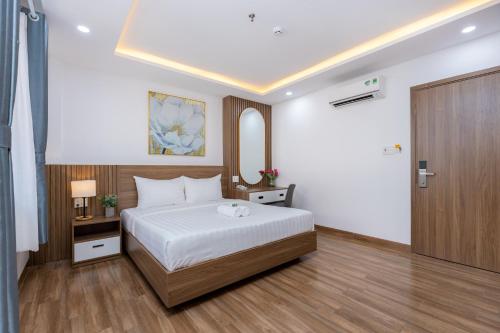 a bedroom with a white bed and a wooden floor at Diamond Sea Hotel in Vung Tau