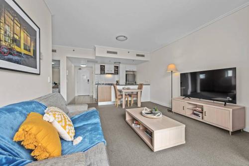a living room with a blue couch and a tv at City Centre! 1Bed/1Bath/Study/1Car/Balcony ~ CBD in Brisbane
