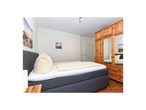 a bedroom with a bed and a wooden cabinet at Friesengold Modern retreat in Bensersiel