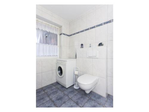 biała łazienka z toaletą i pralką w obiekcie Friesengold Modern retreat w mieście Bensersiel