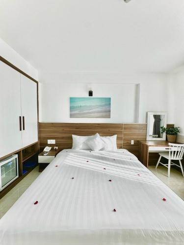 a large white bed in a bedroom with a desk at Tuấn Ninh Hotel I in Con Dao
