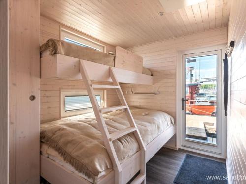 a bunk bed in a wooden room with a window at Houseboat Harmony in Stralsund