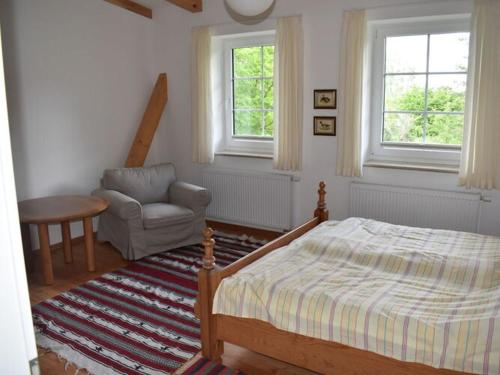 a bedroom with a bed and a chair and two windows at Holiday apartment in Flieth-Stegelitz 