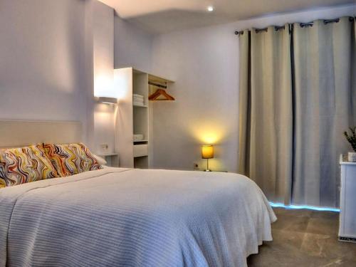1 dormitorio con cama blanca y ventana en Cosy apartment with balcony, en Conil de la Frontera
