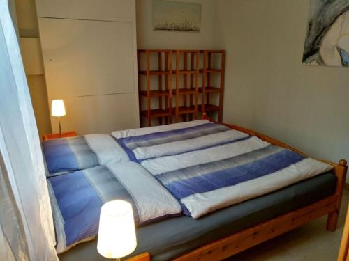 ein Schlafzimmer mit einem Bett mit blauer Bettwäsche und zwei Lichtern in der Unterkunft Am Königsberg, Luebeck in Lübeck