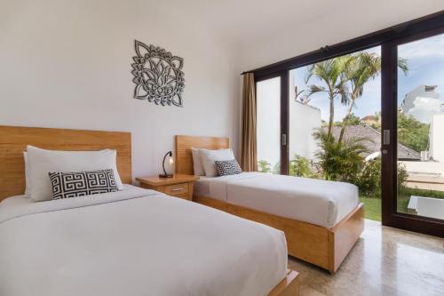 two beds in a room with a large window at Villa Venta by Maheswara in Uluwatu