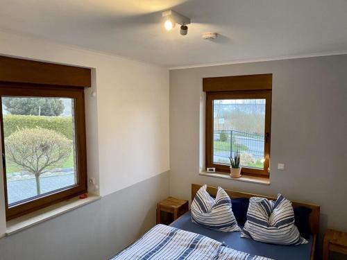 a bedroom with a bed with pillows and two windows at Rügen Apartment Waterview in Buschvitz
