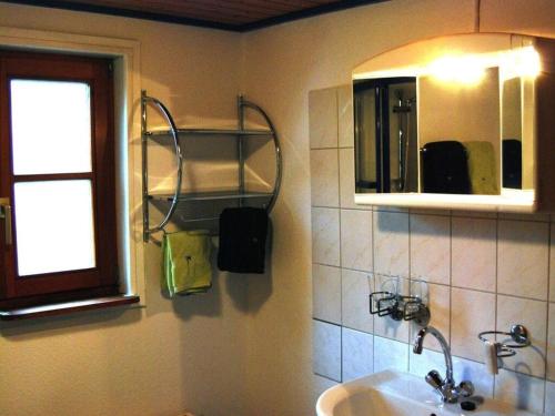 ein Bad mit einem Waschbecken, einem Spiegel und einem Fenster in der Unterkunft little beach flea Comfortable holiday residence in Wangerooge