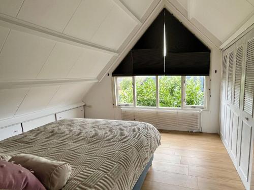 a bedroom with a bed and a large window at Family home near lake, beach and dunes in Noordwijkerhout
