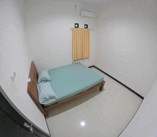 um pequeno quarto com uma cama no canto em Griya Sukoharjo Homestay Jogja em Ngemplak