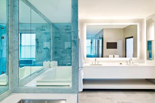uma casa de banho com 2 lavatórios, uma banheira e um espelho. em W Chicago - City Center em Chicago