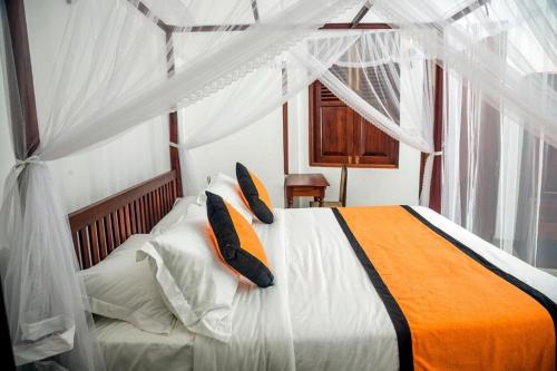 a bedroom with a bed with orange and white pillows at Villa Ramfort, Galle Fort in Galle
