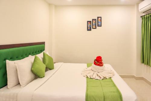 a bedroom with a bed with green and white pillows at SAARA INN in Puducherry