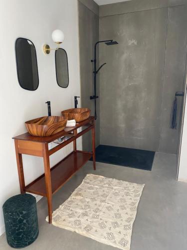 un bagno con doccia e un tavolo in legno con due specchi di Magnifique villa écologique piscine jacuzzi a Clarensac