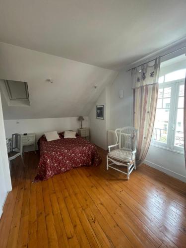 - une chambre avec un lit et une chaise sur du parquet dans l'établissement Jolie maison quartier Vesone, à Périgueux