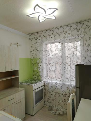 une cuisine avec une cuisinière et une fenêtre dans l'établissement Двухкомнатная квартира в центре города, à Almaty