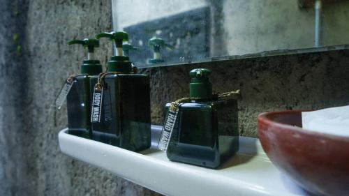 tres botellas de jabón verde sentadas en el lavabo del baño en Baleluhur Villa Ciwidey, en Panundaan