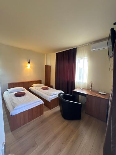 a hotel room with two beds and a chair at Pensiunea Drobeta in Drobeta-Turnu Severin