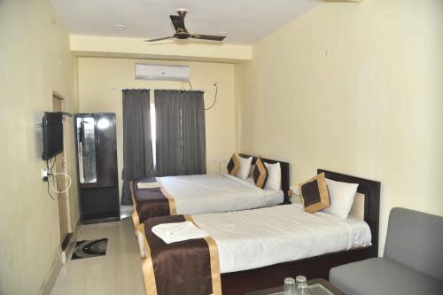 a hotel room with two beds and a chair at Hotel Buddha Vibrant in Deoghar